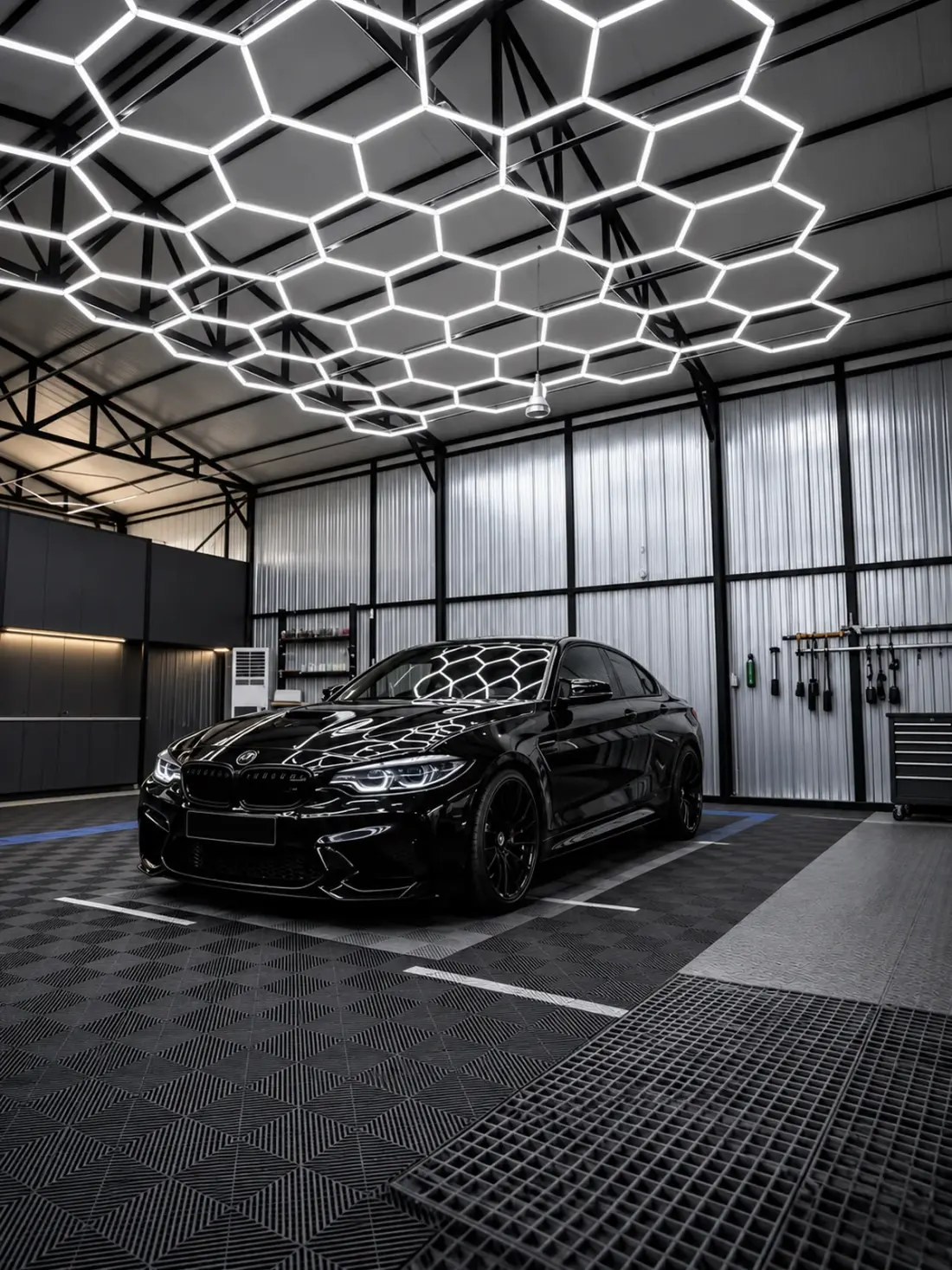 Black car beneath honeycomb LED ceiling lighting in a detailing space